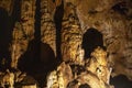 Dark abstract background of stalactites, stalagmites and stalagnates in the Sfendoni cave with a red pointer, underground,