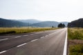 Dark asphalt highway surrounded with forest green field and electric power columns in mountains in Croatia