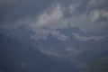 Dark atmospheric surreal landscape with a dark rocky mountain peak in low clouds in a gray cloudy sky Royalty Free Stock Photo