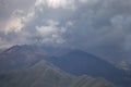 Dark atmospheric surreal landscape with a dark rocky mountain peak in low clouds in a gray cloudy sky Royalty Free Stock Photo