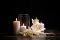 Mortuary urn, burning candles and flowers on table against dark background Royalty Free Stock Photo