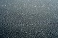 Dark background with large water droplets on newly paved asphalt.