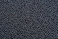 Dark background with large water droplets on newly paved asphalt.