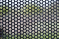 Dark background of metal perforated holes inside which colored background Royalty Free Stock Photo