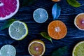 Dark background with slices of tangerines lemons oranges limes citrus fruits and green leaves close up on a wooden background top Royalty Free Stock Photo