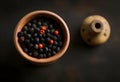 Dark background showing a stone mortar up close and black peppercorns with with space for text Royalty Free Stock Photo