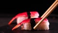 On a dark background on a tray, cooked or purchased sushi Nigiri taste Chinese chopsticks. Concept of: Nigiri, Sushi of the Day,