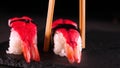 On a dark background on a tray, cooked or purchased sushi Nigiri taste Chinese chopsticks. Concept of: Nigiri, Sushi of the Day,