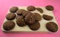 Dark baked chocolate cookies on wooden cutting board on pink acrylic background. Top view. Food photography, dessert, snack, cafe Royalty Free Stock Photo