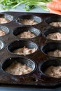 A dark baking muffin tin filled with carrot cake muffin batter.