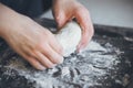 On a baking tray, sprinkled with flour, a man knead dough with his hands. The process of cooking at home Royalty Free Stock Photo