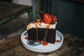 Dark beer chocolate cake on white plate and decorated with strawberries, blueberries and pistachio