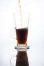 Dark beer is poured into a mug on a white background