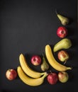 On a dark black background red yellow apples pears bananas frame view from above flat lay vertical Royalty Free Stock Photo