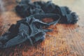 Dark black jean denim fabric scraps laying on a brown wooden table surface