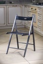 Dark black polished lacquered comfortable simple wooden folding chair, over out of focus interior kitchen background