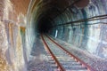 Dark black shaded tunnel in an underground tunnel in a cavern of a railway along the tracks of a train towards the station Royalty Free Stock Photo