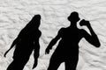 Dark black silhouette of a guy and a girl shade on a white beach sand background