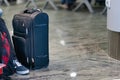 A suitcase sits next to a tourist at an airport as the wait to board a plane at Prague International Airport