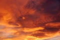 Dark blood red sky background. Dramatic heavy clouds with the hint of the sun at sunset. Many orange tones and patterns of clouds Royalty Free Stock Photo