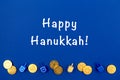 Dark blue background with multicolor dreidels and chocolate coinsand Happy Hanukkah wording. Hanukkah and judaic holiday Royalty Free Stock Photo