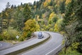 Dark blue big rig semi truck transporting cargo in refrigerator semi trailer running on the turning multiline highway road with Royalty Free Stock Photo