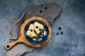 Dark blue bowl of oatmeal porridge with banana and blueberry on vintage table top view in flat lay style. Hot breakfast Royalty Free Stock Photo