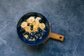 Dark blue bowl of oatmeal porridge with banana and blueberry on vintage table top view in flat lay style. Hot breakfast Royalty Free Stock Photo