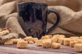 Dark blue ceramic tea mug, cookie sticks with chocolate and white icing and brown cane sugar pieces on a wooden background. Close Royalty Free Stock Photo