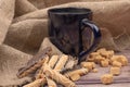 Dark blue ceramic tea mug, cookie sticks with chocolate and white icing and pieces of brown cane sugar on a background of textured Royalty Free Stock Photo