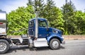 Dark blue day cab big rig semi truck with aluminum steps transporting liquid cargo in shiny tank semi trailer running on the Royalty Free Stock Photo