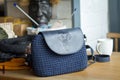 A dark blue knitted bag with a leather insert and an elephant print on a light wooden surface. Workplace in the process of Royalty Free Stock Photo