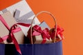 Dark blue paper shopping bag full of gift boxes on orange background, closeup Royalty Free Stock Photo