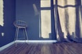 Dark blue room with modern chair on high legs, metal frame with soft cushion,seat, curtains, window shadow, wooden floor Royalty Free Stock Photo