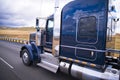 Dark blue shiny classic big rig semi truck running on the road w Royalty Free Stock Photo