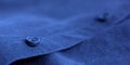 Dark blue shirt button on fabric texture textile material blurred background Royalty Free Stock Photo