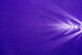 On a dark blue structural fine-grained background, a light purple scattered beam of light Royalty Free Stock Photo