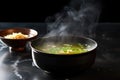 dark bowl of miso soup with steam rising on a cool slate counter