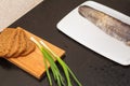 Dark bread and green onions are on the cutting Board. which is lying on a dark table, on the table is a cleaned fish Royalty Free Stock Photo