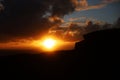 Dark bright sunset with clouds, silhouette of a rock, voluminous clouds