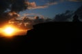 Dark bright sunset with clouds, silhouette of a rock, voluminous clouds