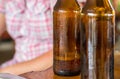 Dark brown bottle with a piece of beer with foam and empty on a wooden table on a blurred background Royalty Free Stock Photo