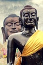 Dark Brown Budha statue with another Budha looking over his shoulder Royalty Free Stock Photo