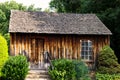 A dark brown cabin surrounded by green trees and green plants