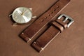 Dark brown leather watch strap with stainless buckle on leather background, Craft and handmade watch bracelet