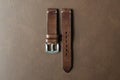 Dark brown leather watch strap with stainless buckle on leather background, Craft and handmade watch bracelet.