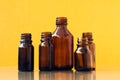 Dark brown phials on yellow background. Small empty bottles Royalty Free Stock Photo