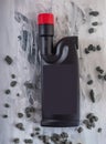 A dark brown plastic bottle with a red lid with gel for cleaning pipes, decorative pebbles