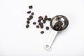 Dark brown quality of coffee beans in a stainless one tablespoon measuring and some are out from spoon on white background Royalty Free Stock Photo