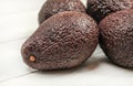 Dark brown ripe avocados on white boards. Close up, detail on skin texture visible